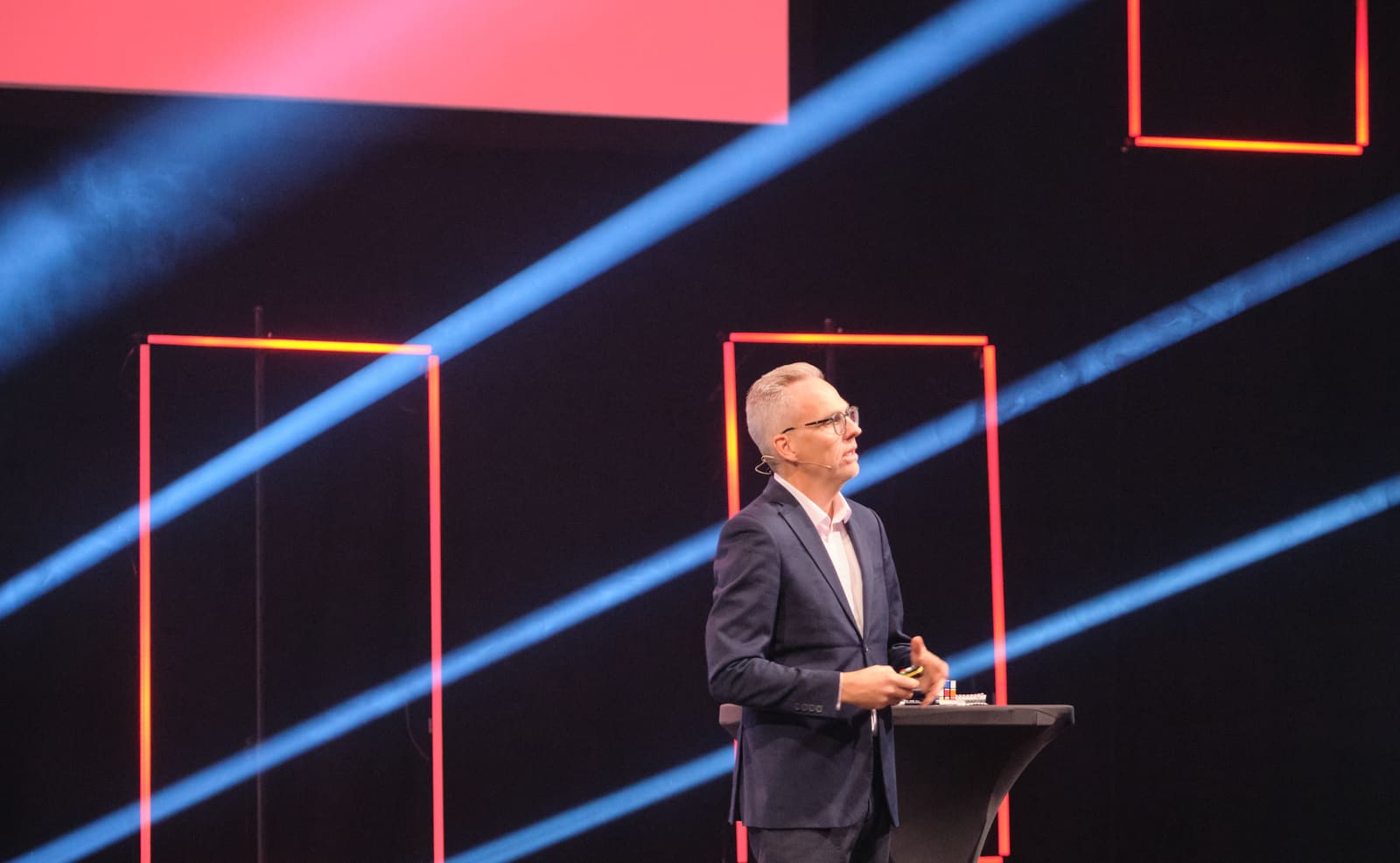 Rune Carlsen på scene foran publikum med lys og scenografi.