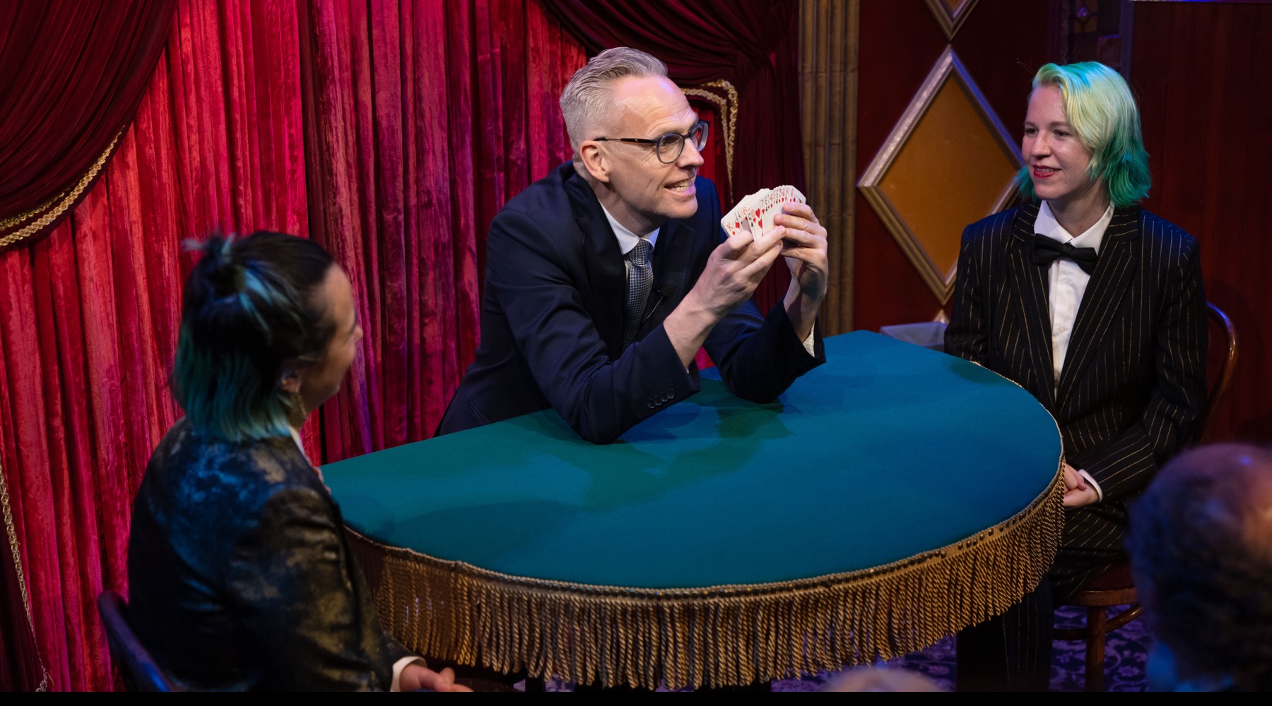 Rune Carlsen underholder tett på gjestene med kortmagi rundt et bord.